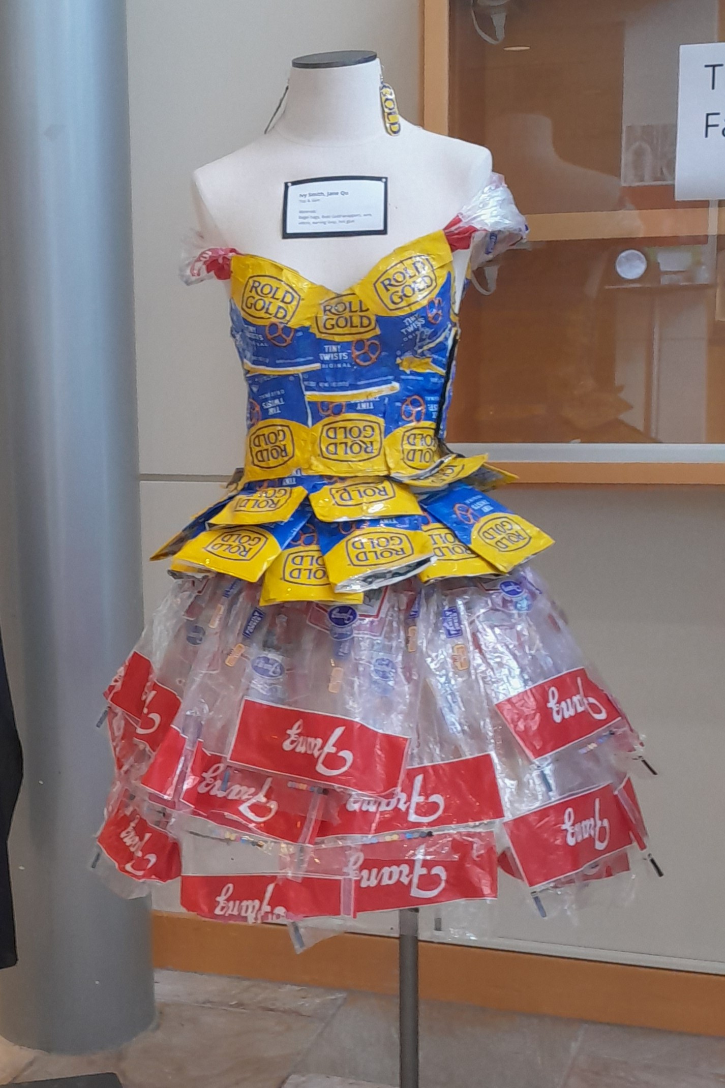 Bodice and skirt by 8th grade art students, created for class trashion show. Dress was designed to show consumer waste, and was made entirely from school snack wrappers: pretzel wraps and plastic bagel bags. This outfit also utilized innovative construction techniques, as plastic wraps were fused together to create a molded fabric.